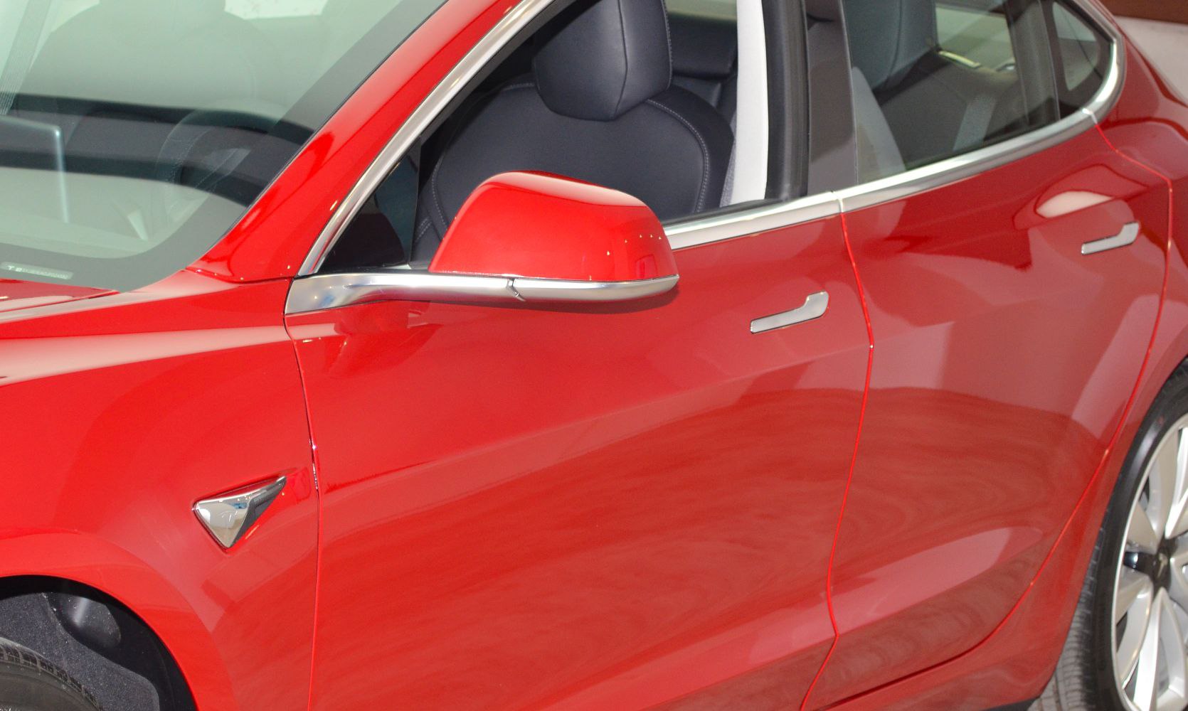 Side mirror, door handles, and wheel of red car
