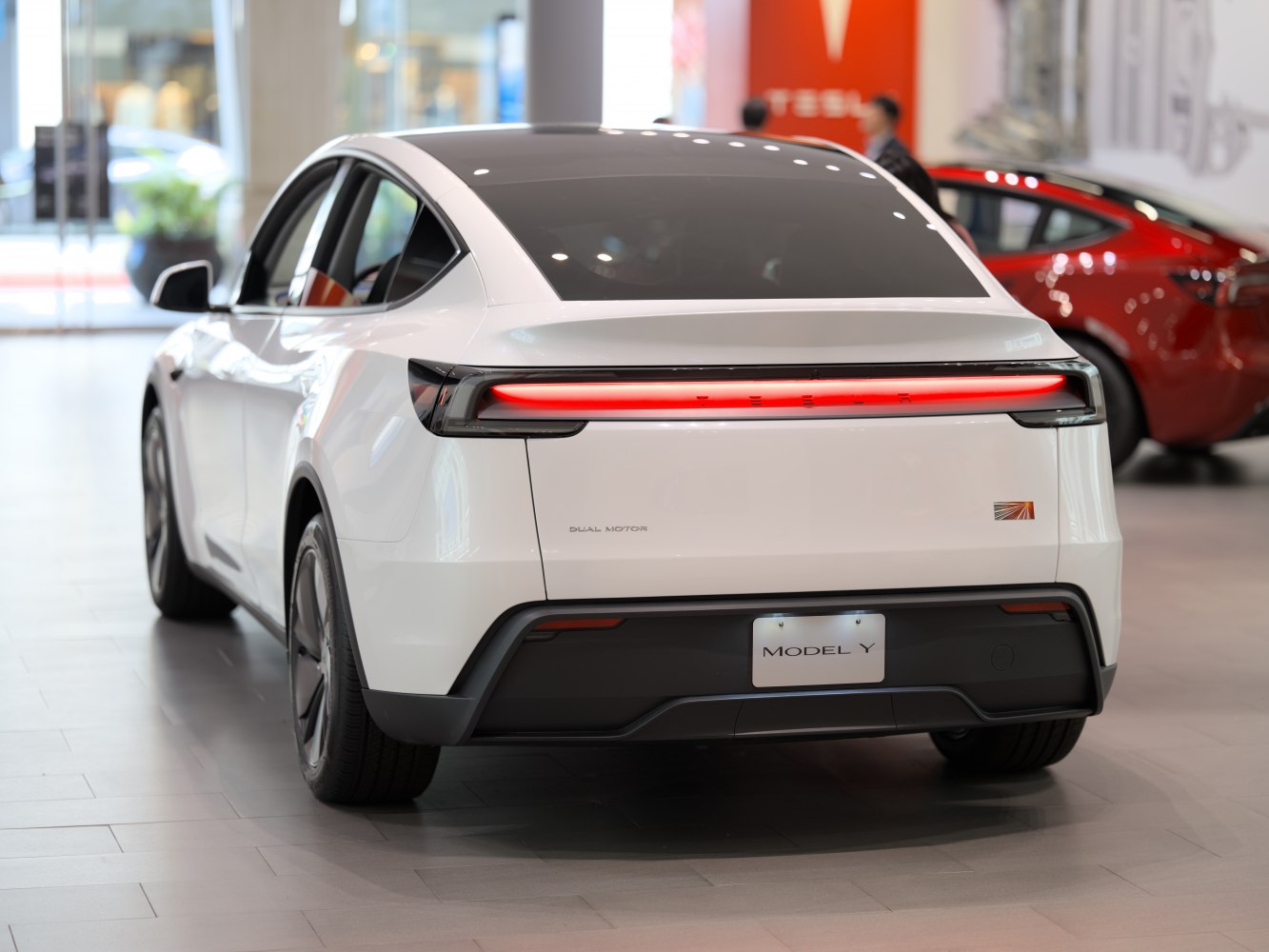 Rear view with illuminated horizontal taillight strip and dual motor badge.