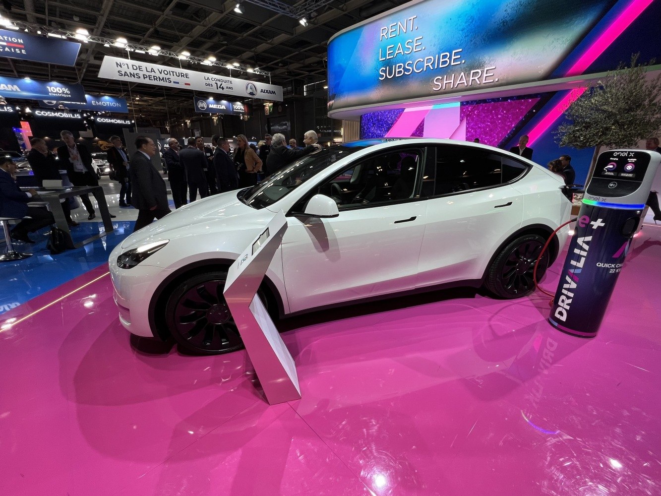 White electric SUV charging at a quick charge station on a glossy pink floor