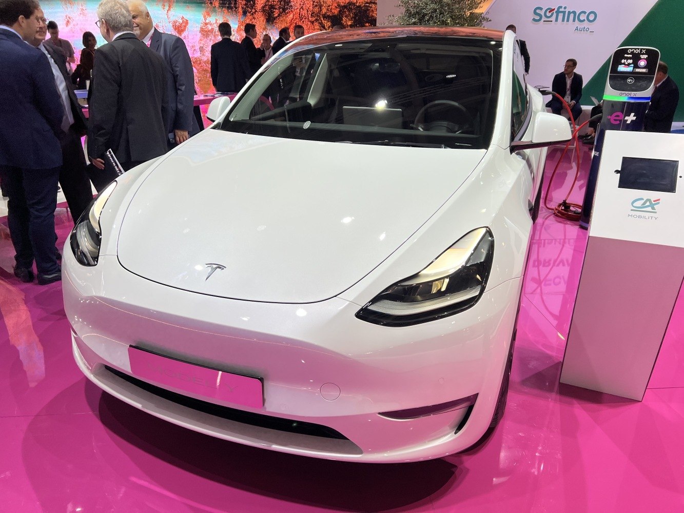 White electric SUV front view with sleek headlights, charging at station