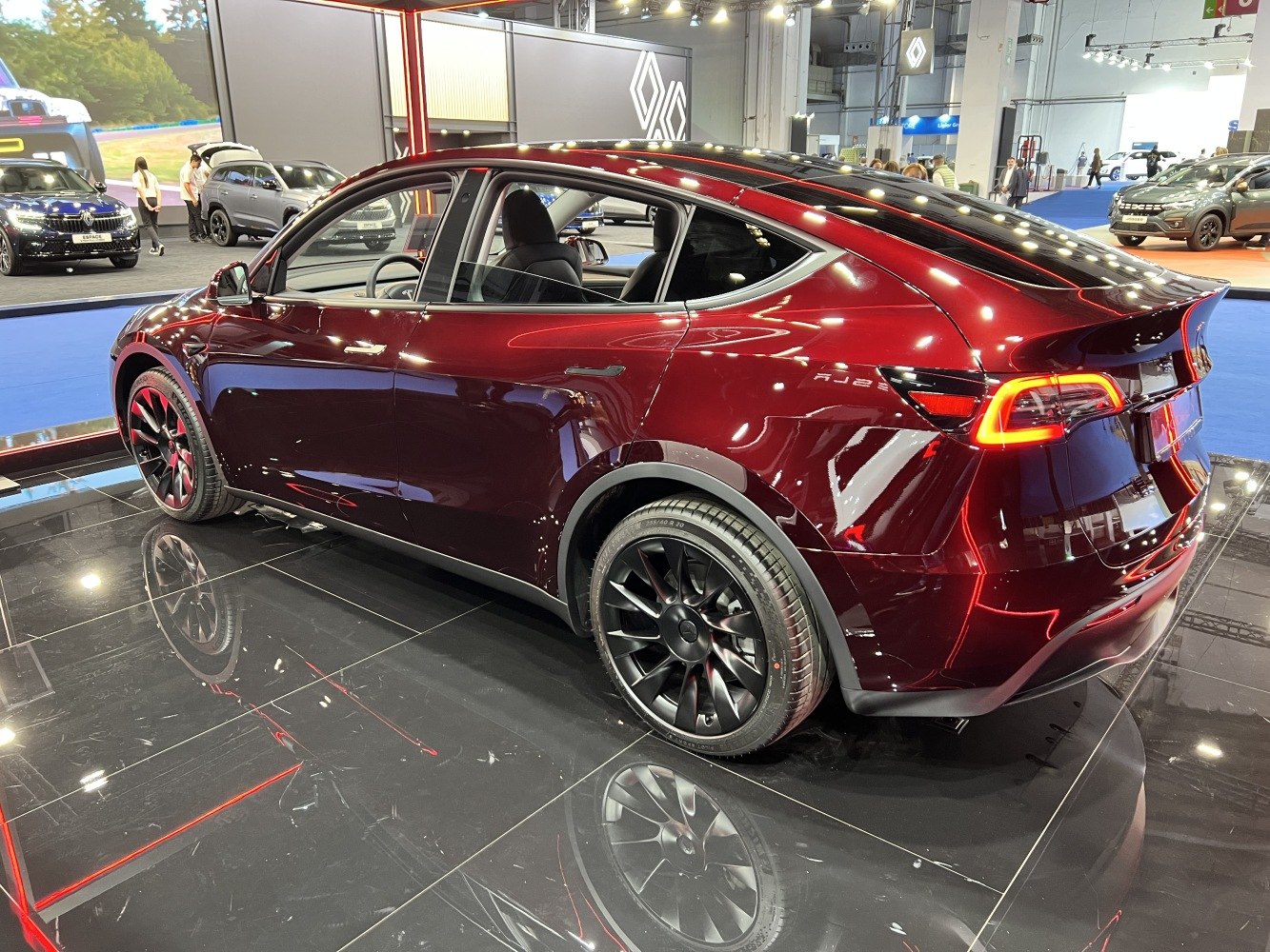 Rear side view of dark red electric SUV with aerodynamic shape and modern taillights.