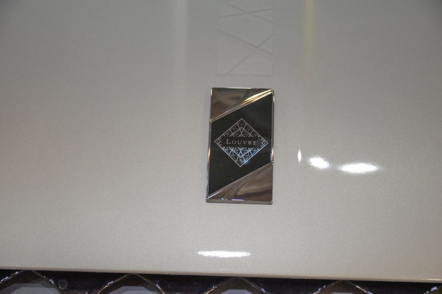 Close-up of a rectangular Louvre edition badge on glossy surface