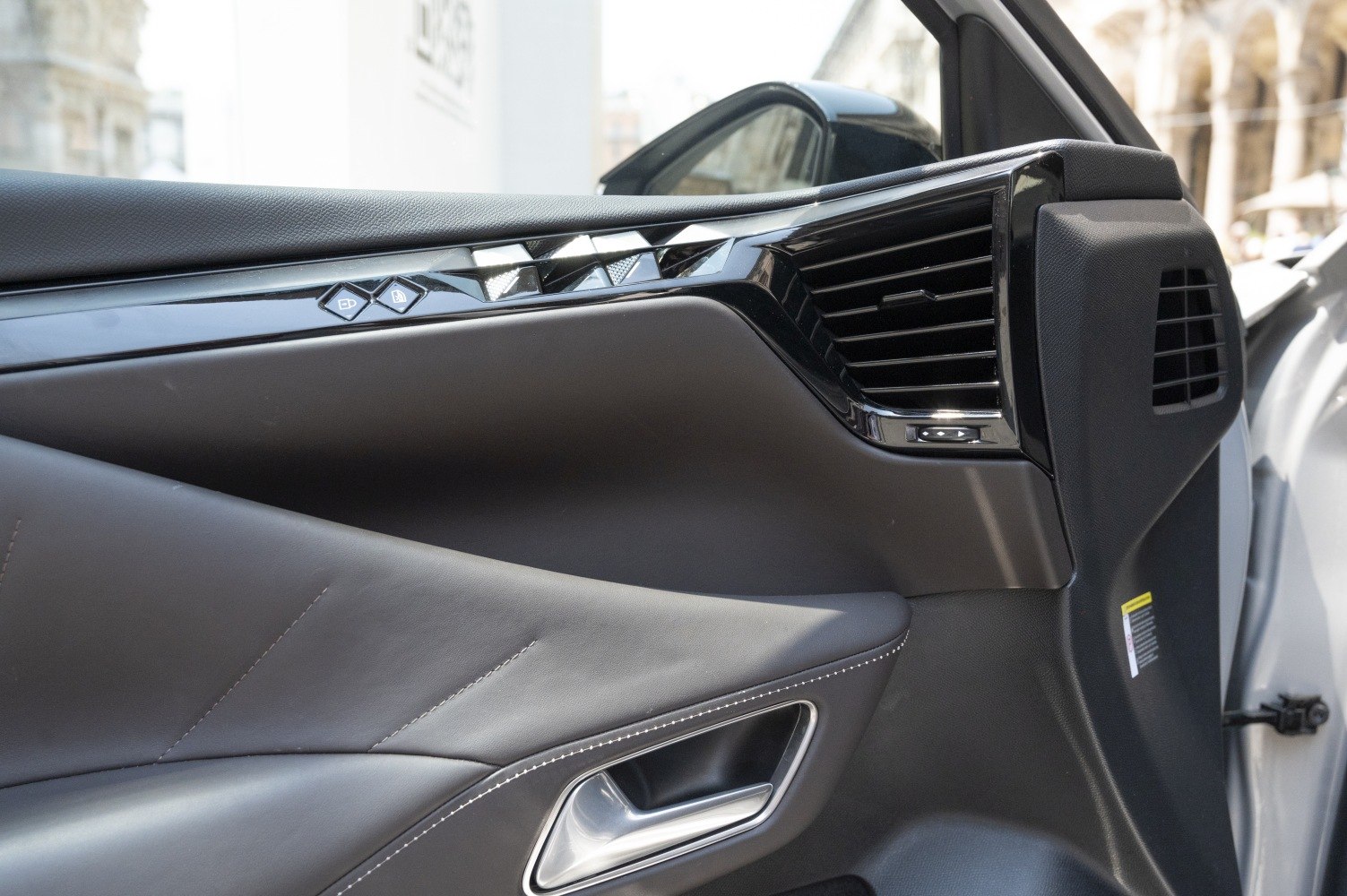 Close-up of modern car door panel with controls and air vent