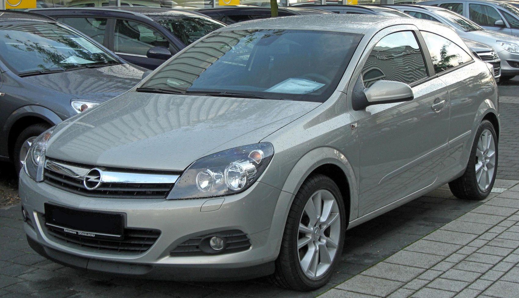 Front and side view of a sporty hatchback with rain droplets on surface