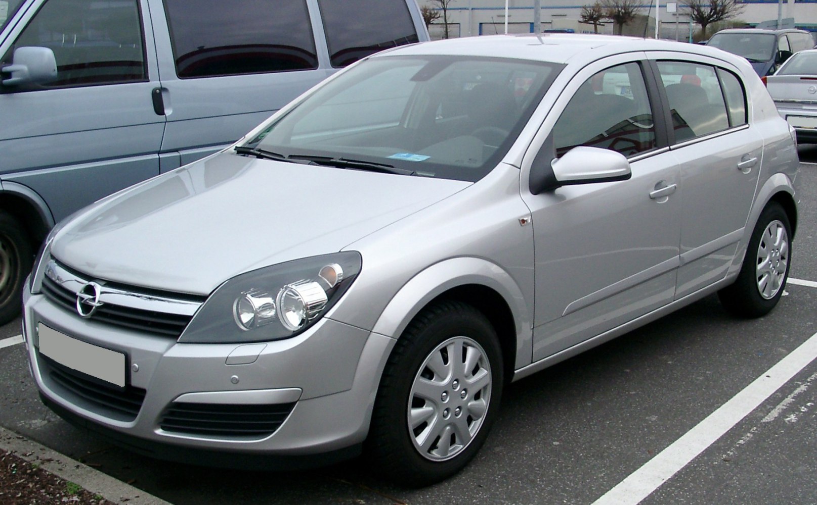 Silver compact hatchback front view with headlights and side mirror