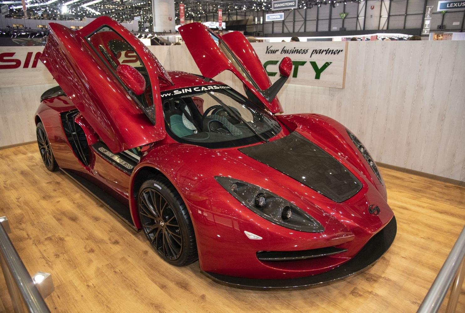 Red sports coupe with gullwing doors and carbon fiber hood.