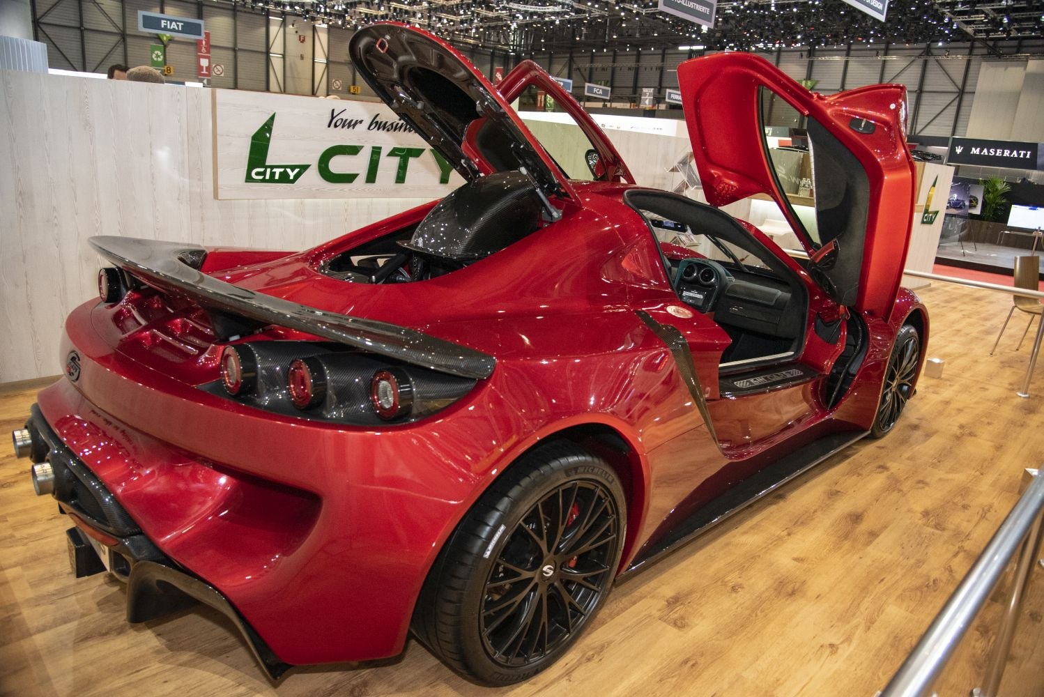 Rear spoiler, quad exhausts, and scissor doors on a red sports coupe