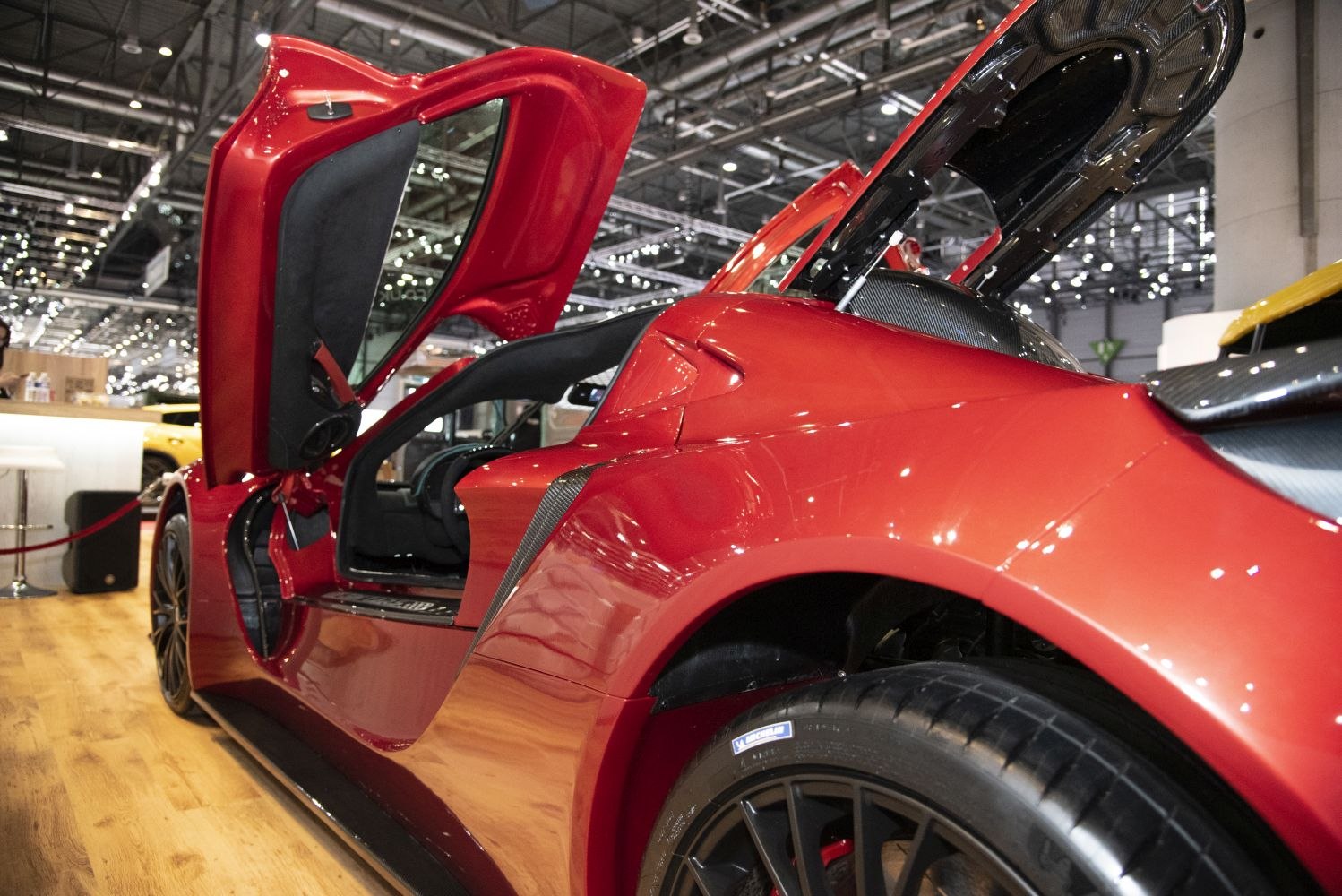 Red sports car with open scissor doors and aerodynamic rear design