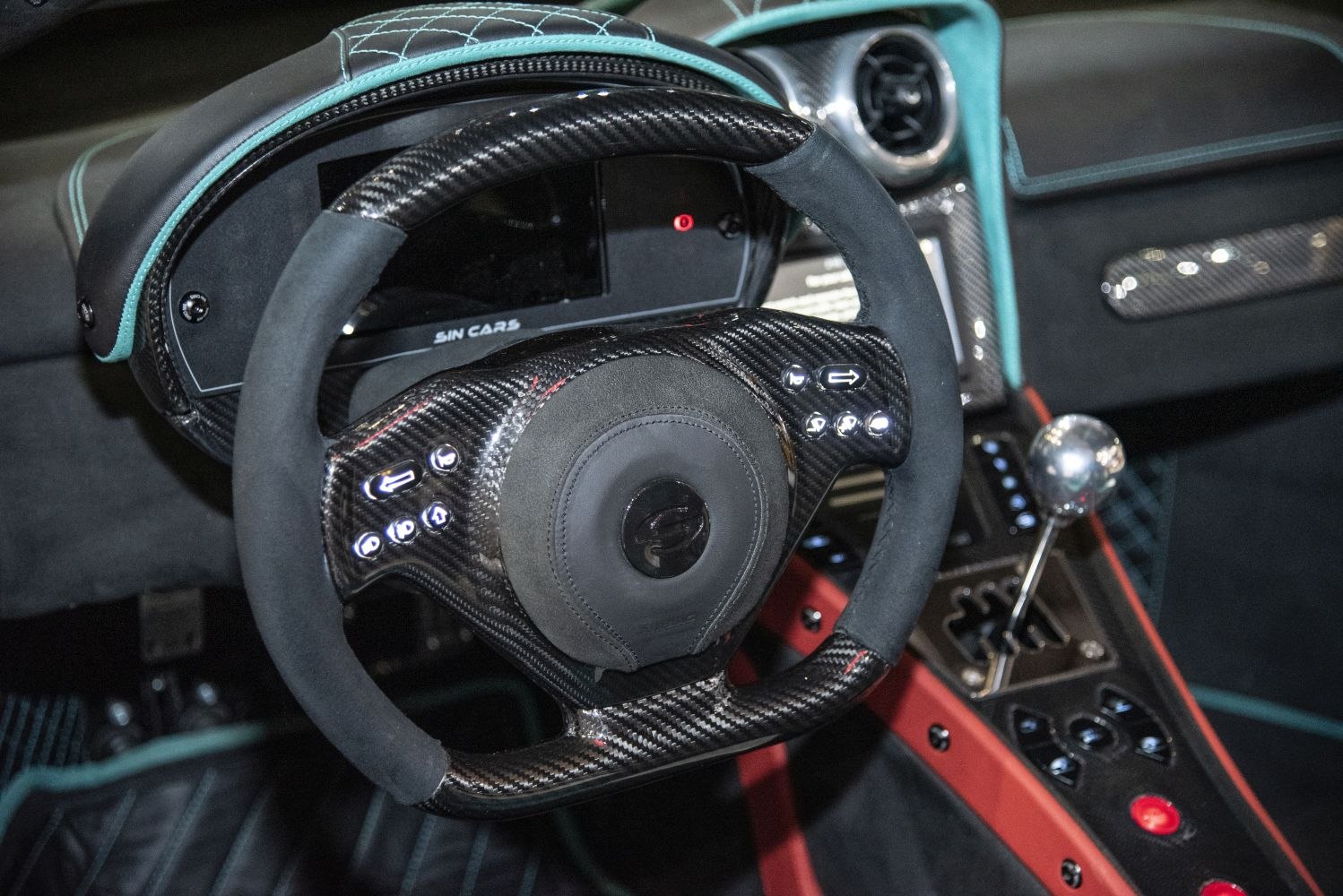 Carbon fiber steering wheel with control buttons and manual gear shifter in a sporty car interior