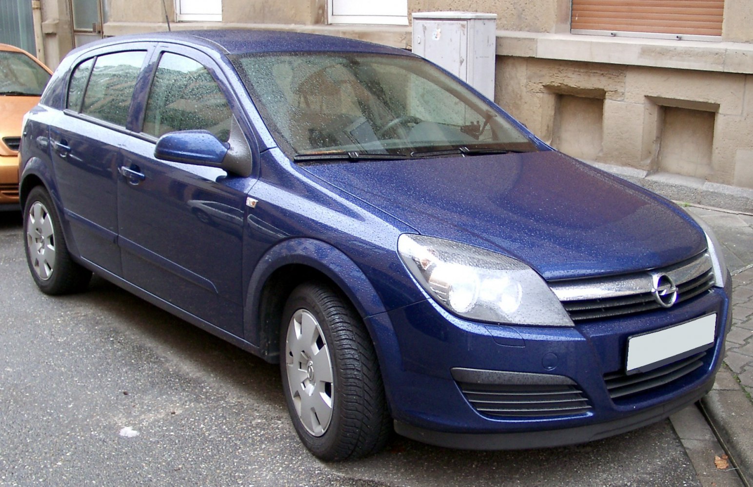 Blue hatchback with front-side view and rain droplets