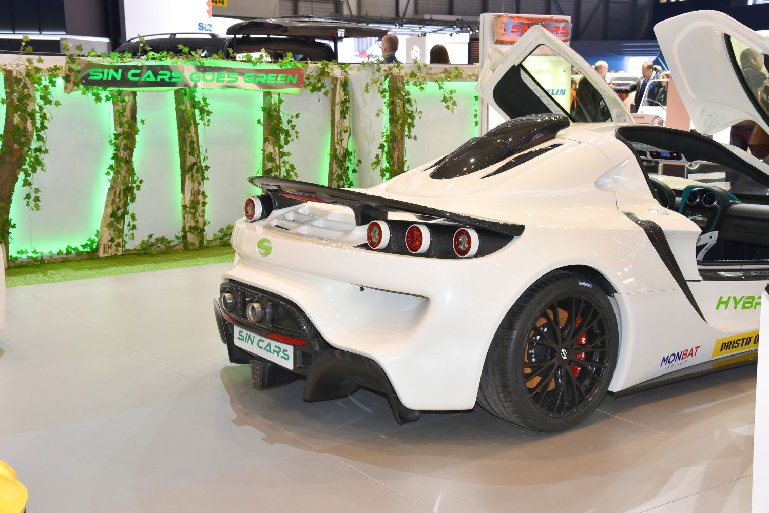 Rear view with quad round taillights and large rear wing on white sports coupe.