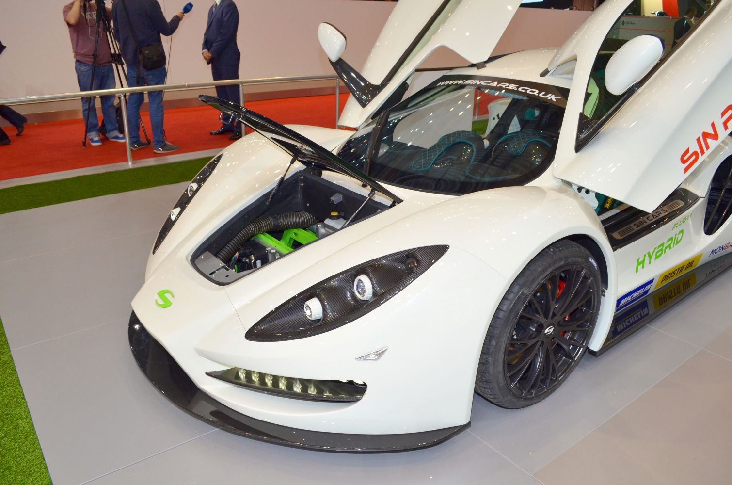 Open gullwing doors and exposed front hood with headlights and hybrid components