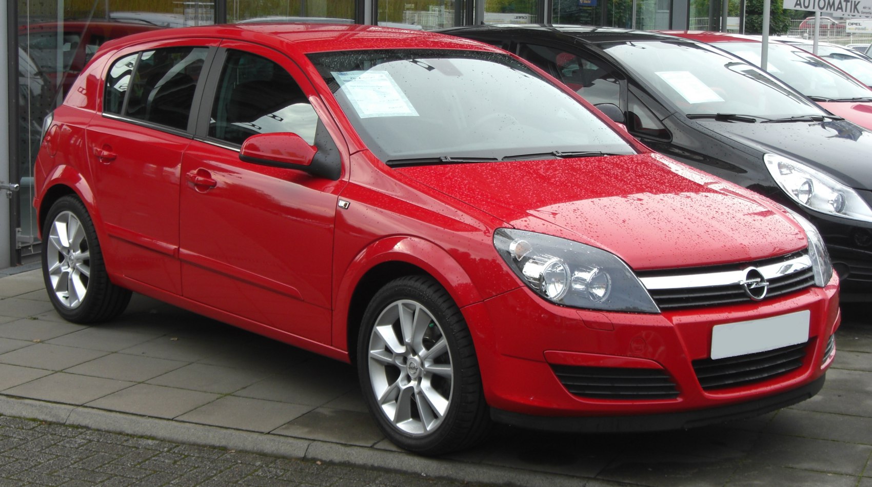 Red 5-door hatchback with alloy wheels and prominent headlights