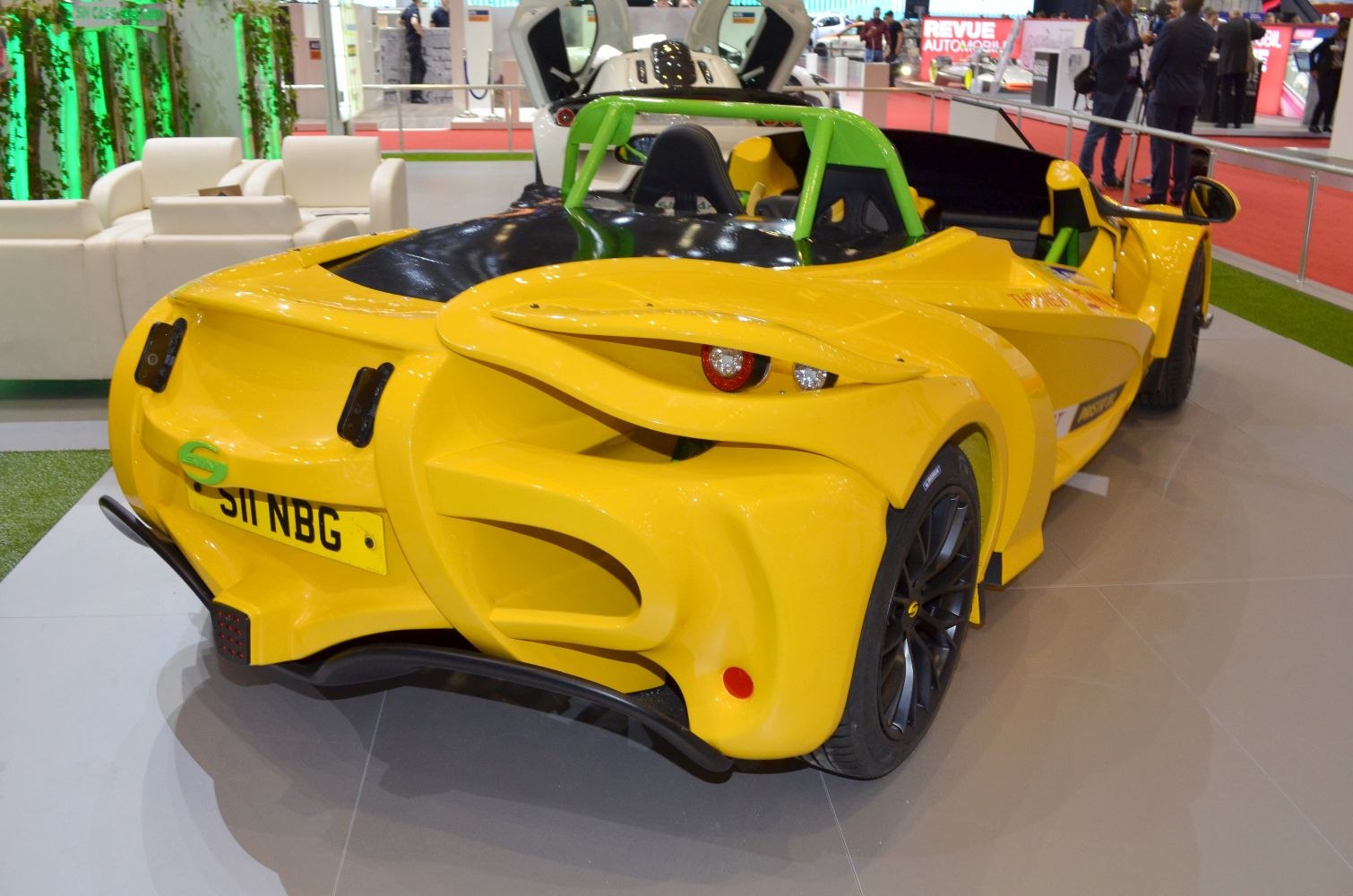 Yellow open-top roadster rear with aerodynamic design and green roll bar