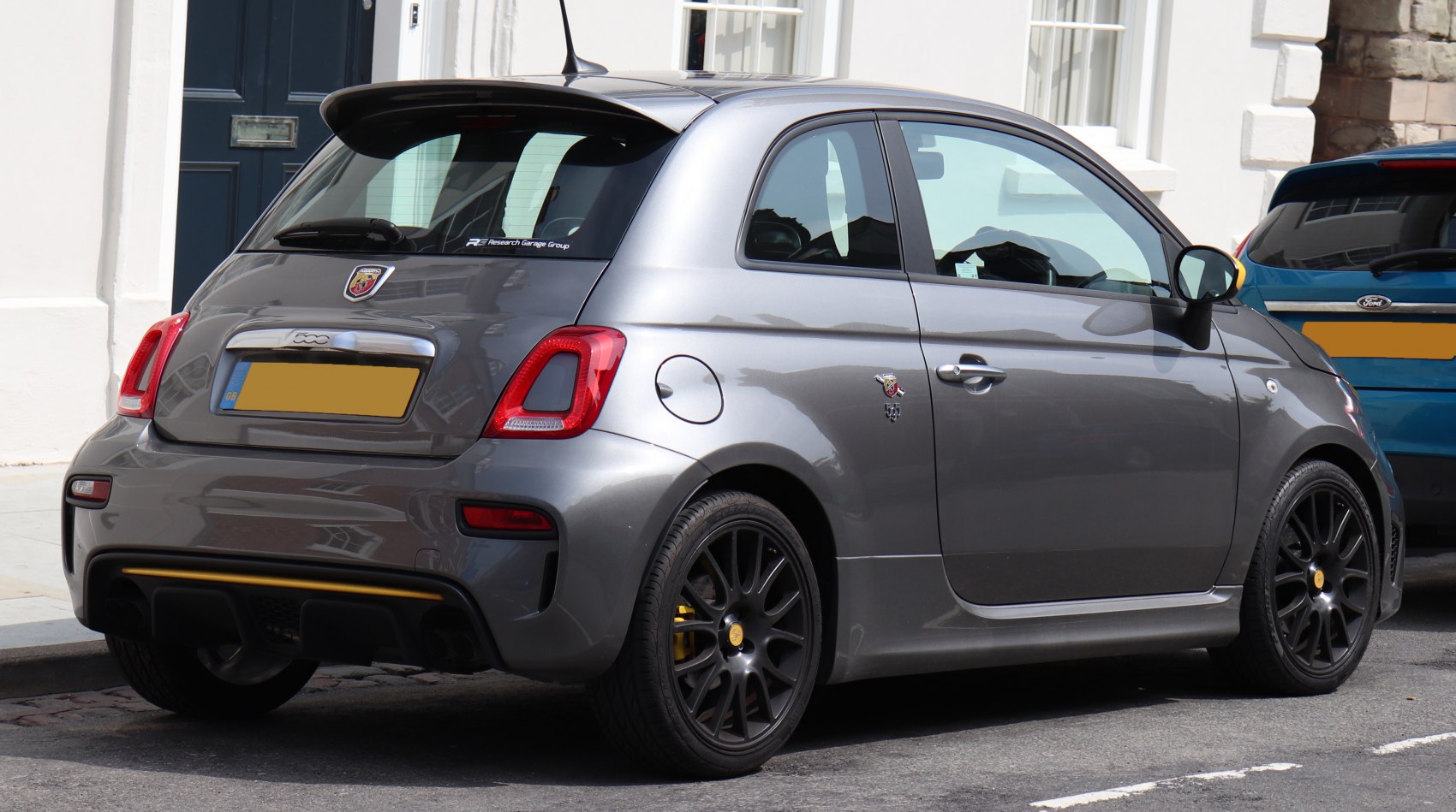 Rear side view of a sporty compact hatchback with black alloy wheels and rear spoiler