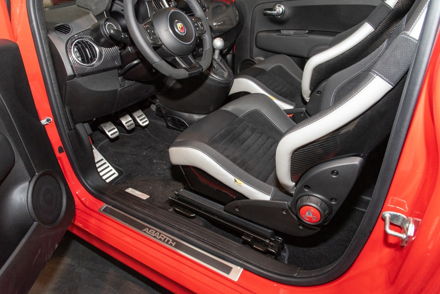Sporty carbon fiber bucket seats and manual gearbox inside a compact car.