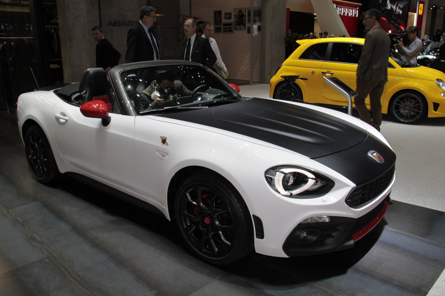 Convertible with black hood, red mirrors, and black wheels.