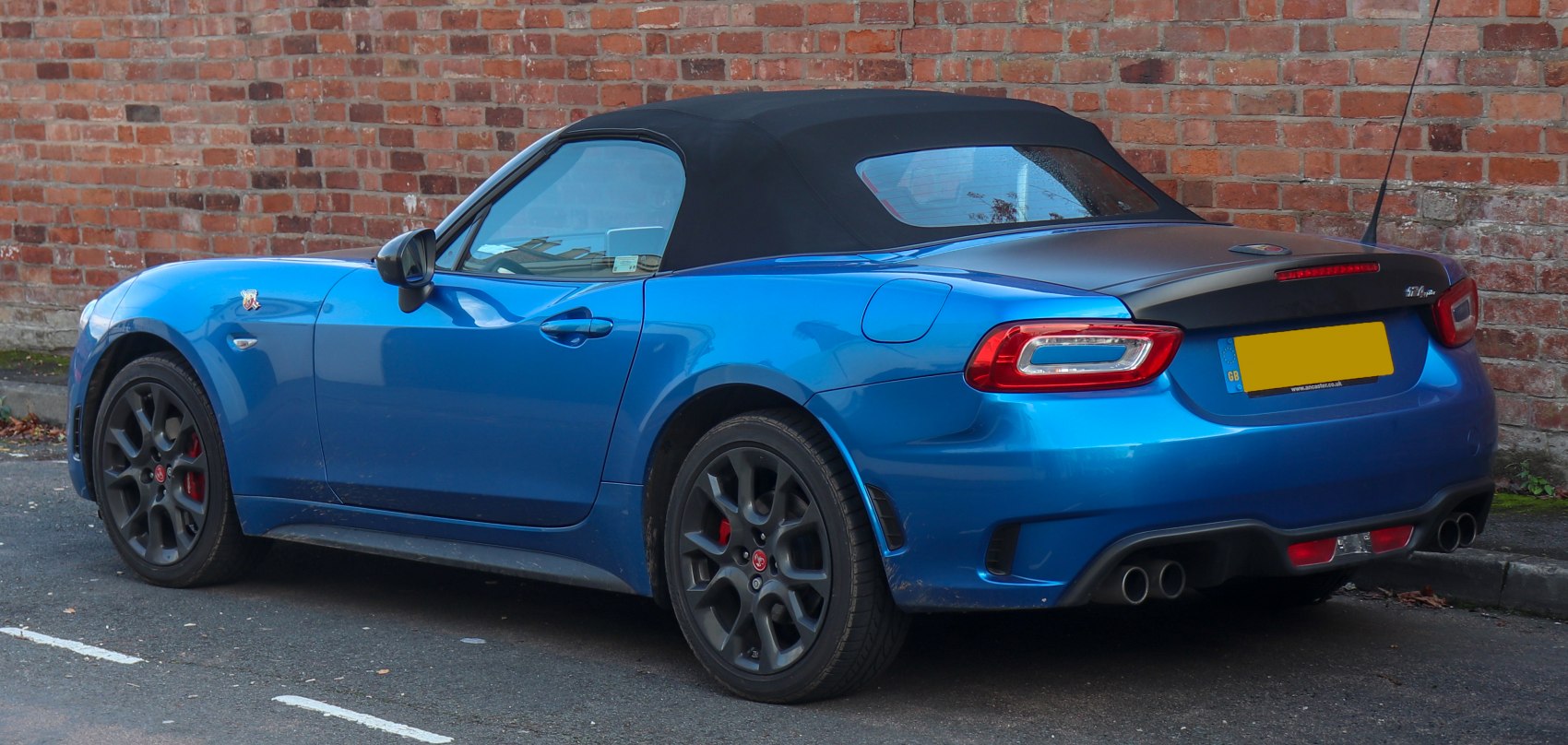 Blue convertible with black soft top and quad exhaust system