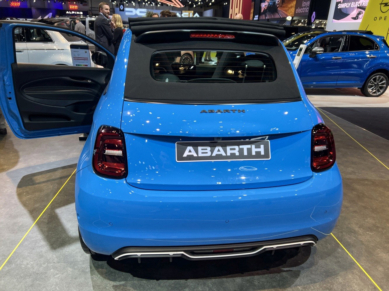 Rear view of blue convertible with folded soft top and illuminated taillights