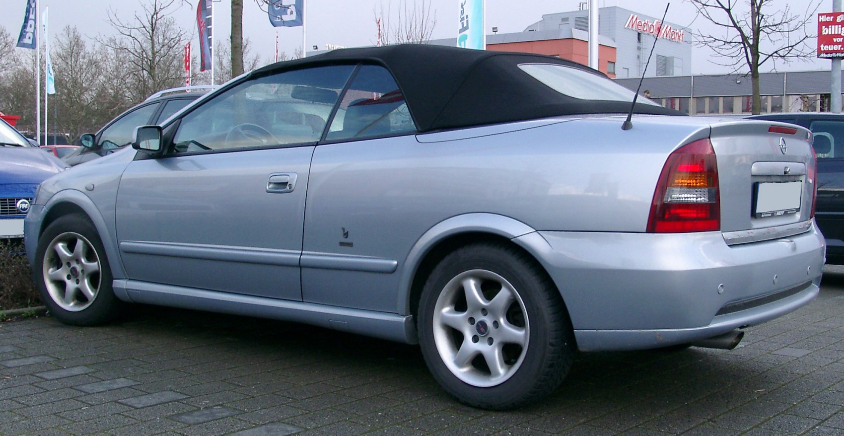Silver two-door convertible with black soft top and alloy wheels