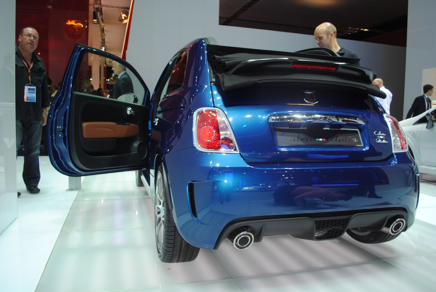 Rear view of blue convertible hatchback with open door and dual exhaust