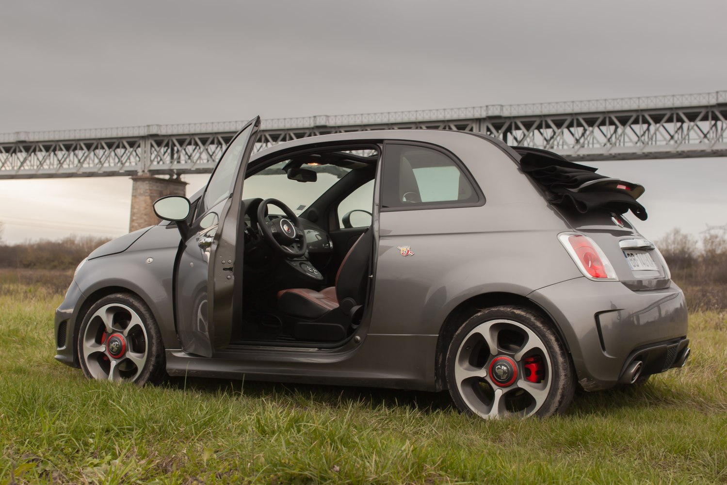 Sporty convertible compact with open door and folded soft top roof