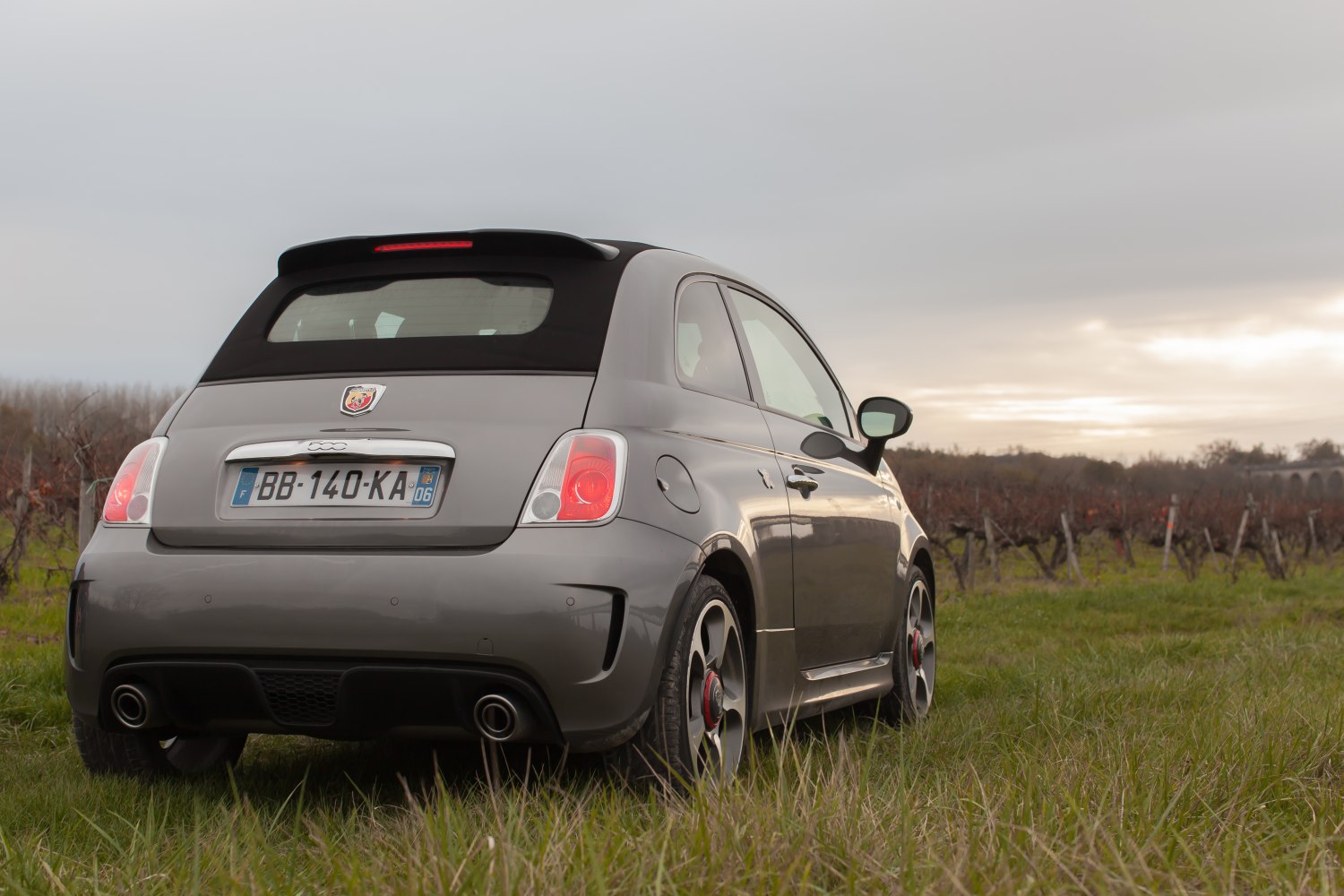 Compact convertible with dual exhaust and rear spoiler in outdoor setting