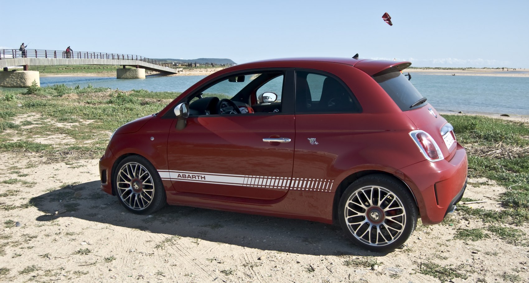Compact red hatchback with racing stripes and sporty alloy wheels