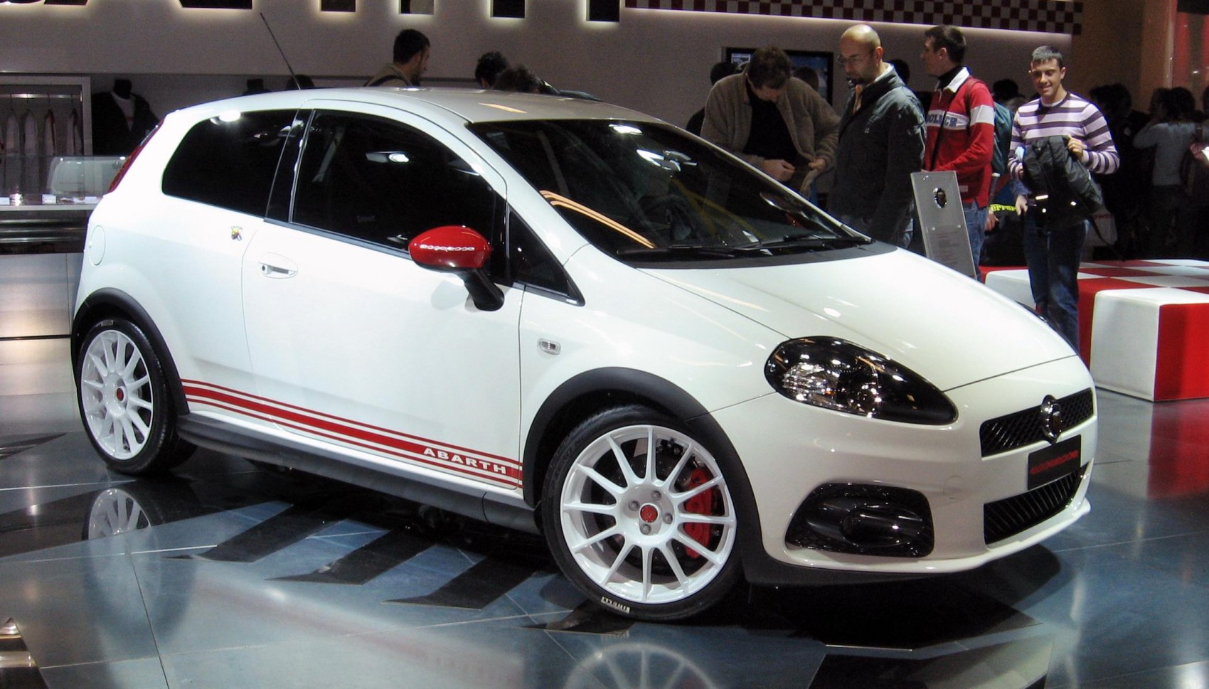 Sporty hatchback with red stripes, white multi-spoke wheels, and red side mirrors