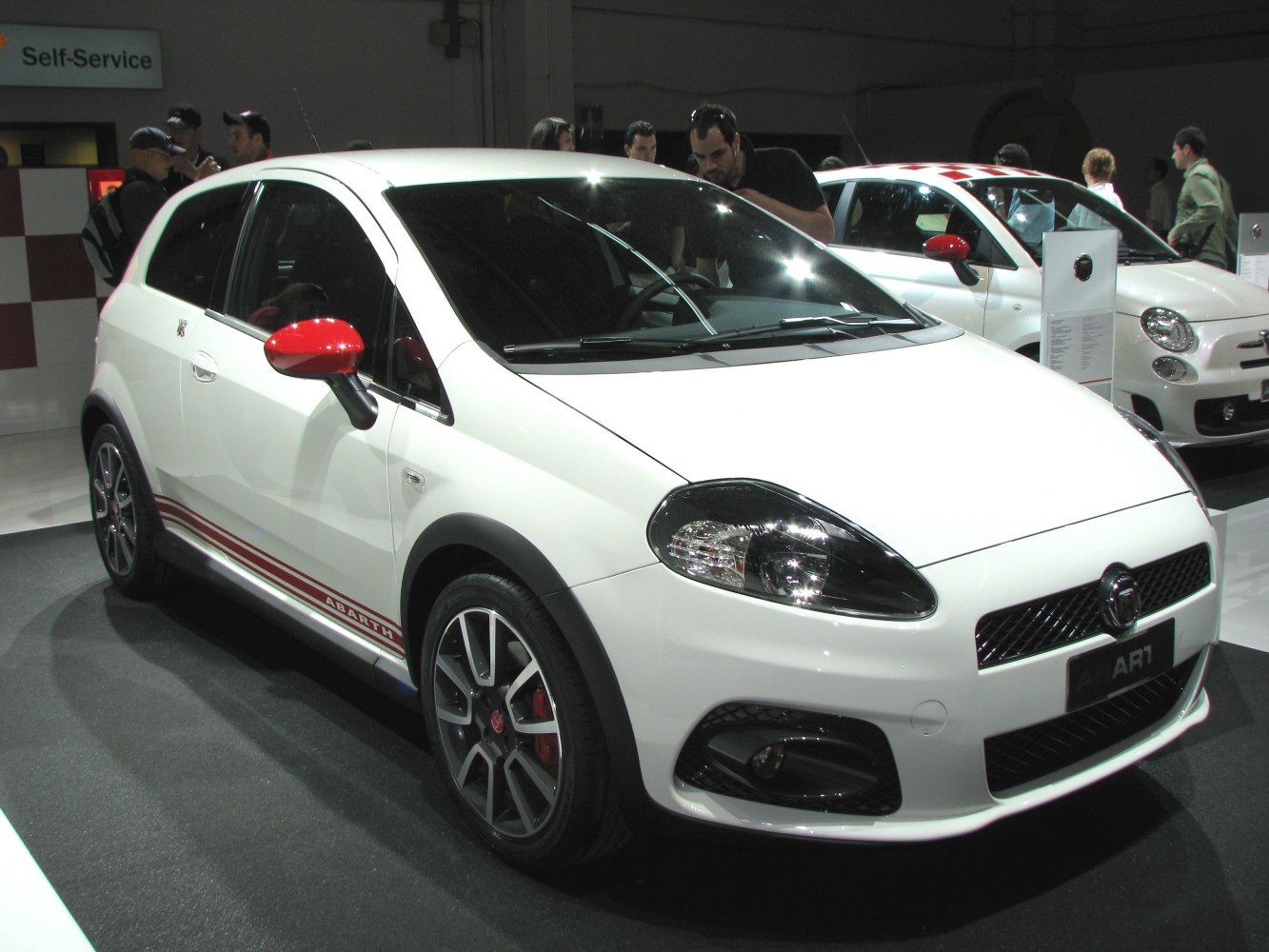 Sporty white hatchback with red mirror caps and alloy wheels front three-quarter view