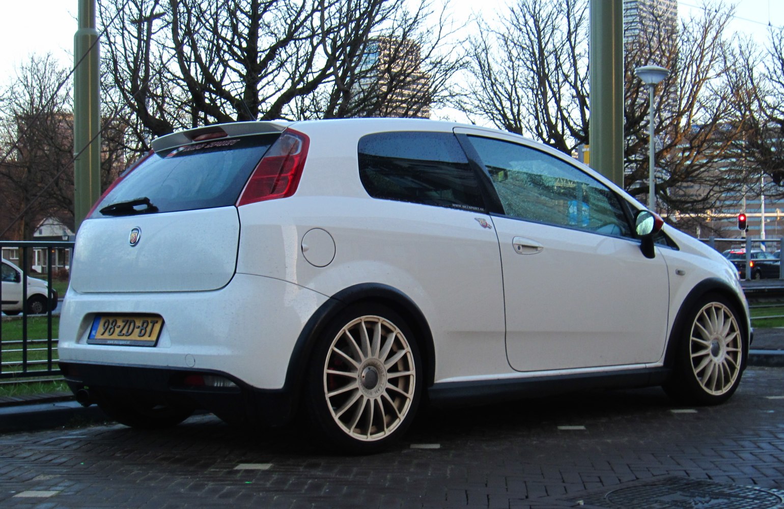 White hatchback with rear spoiler and multi-spoke wheels
