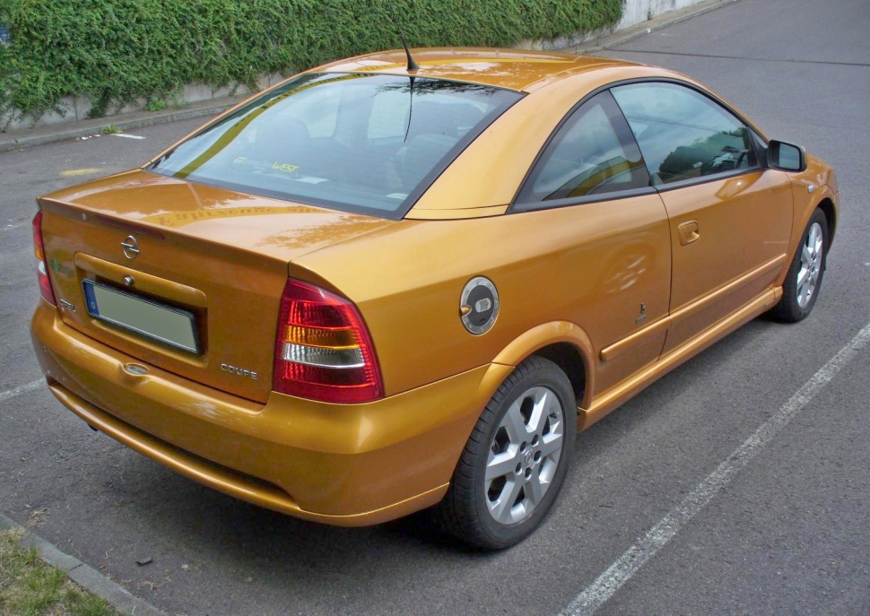 Rear and side view of a gold Opel Astra G Coupe with distinct tail lights and fuel cap.