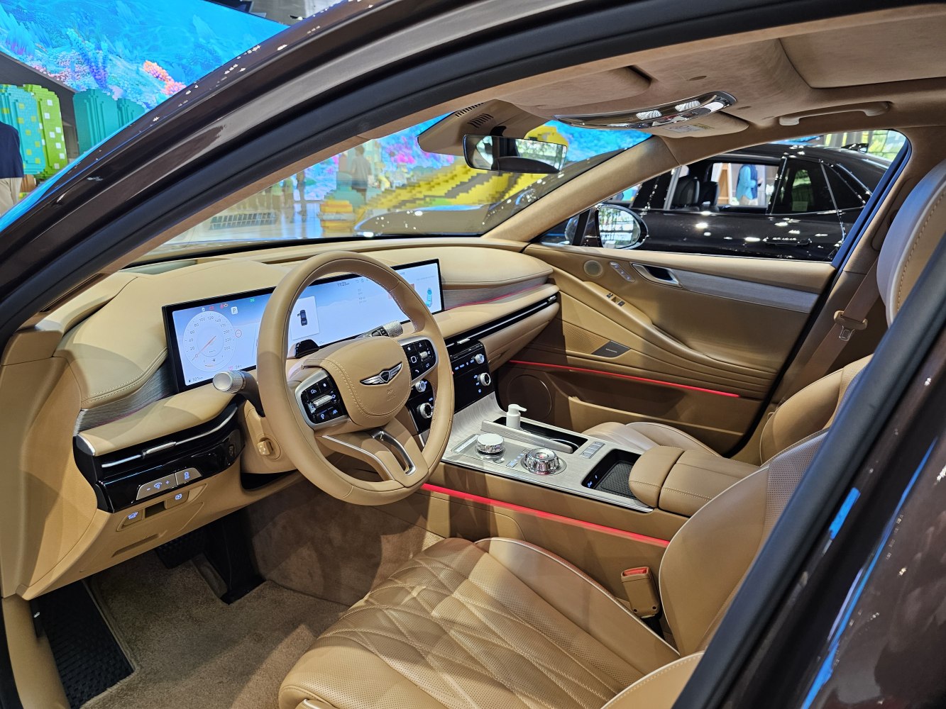 Luxurious beige leather interior with dual digital displays and illuminated ambient red lighting