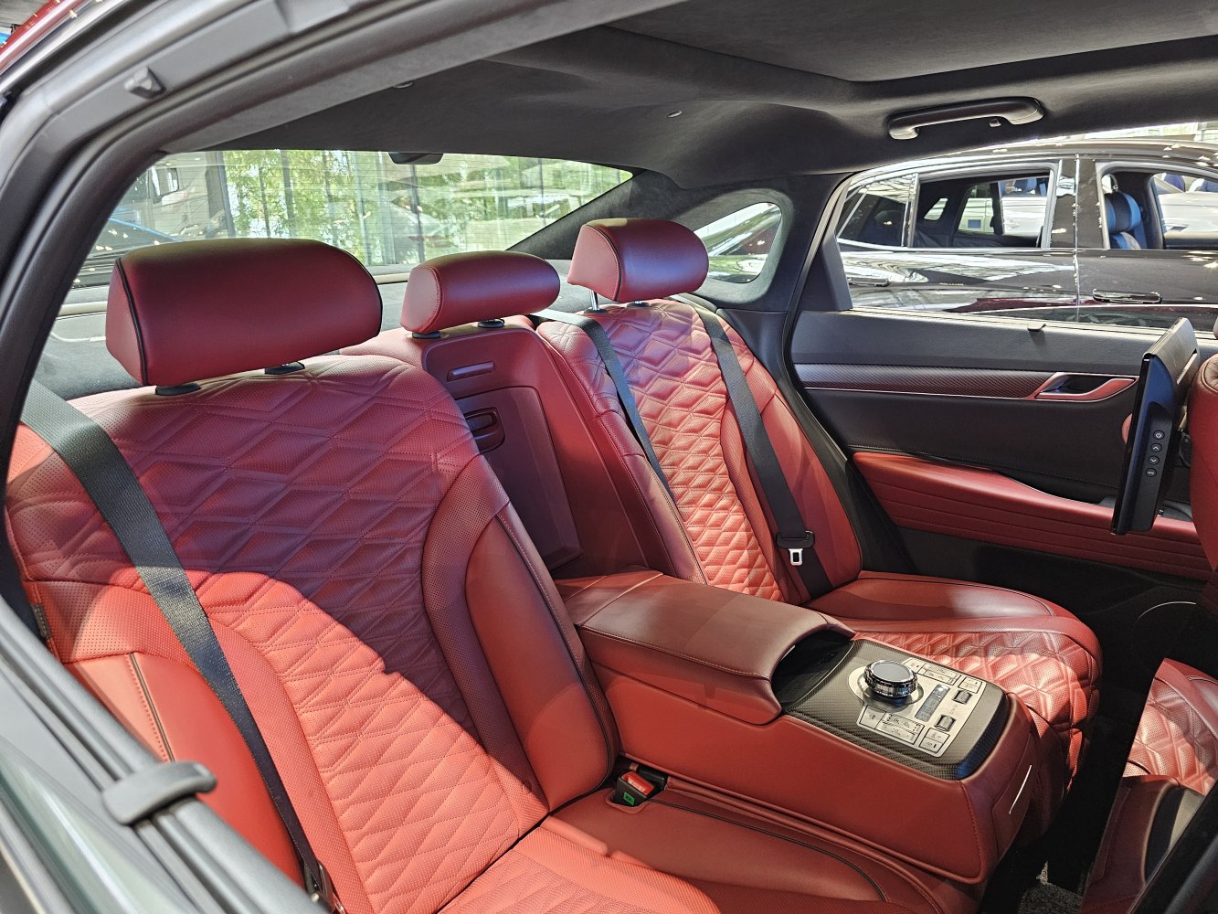 Quilted red leather rear seats with central control panel and rear entertainment screen.