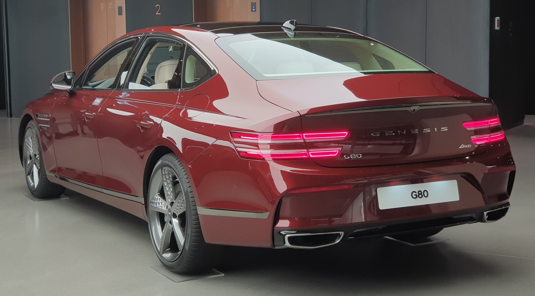 Rear view of a red luxury sedan with LED tail lights and multi-spoke alloy wheels.