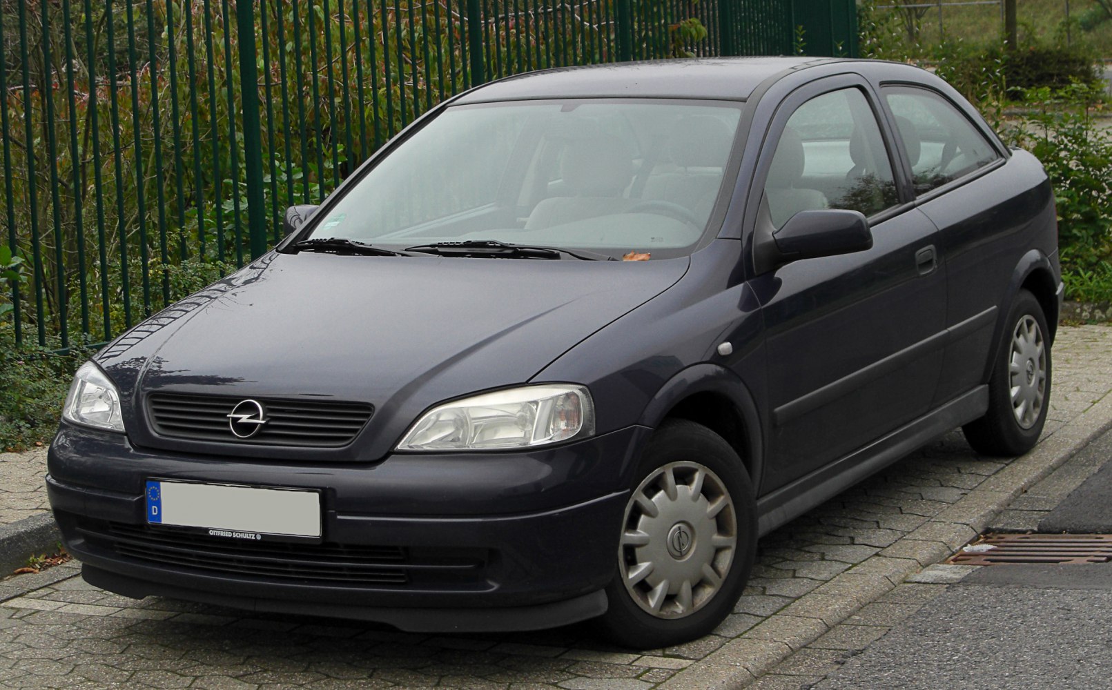Dark 3-door hatchback front side with wheel hubcaps.