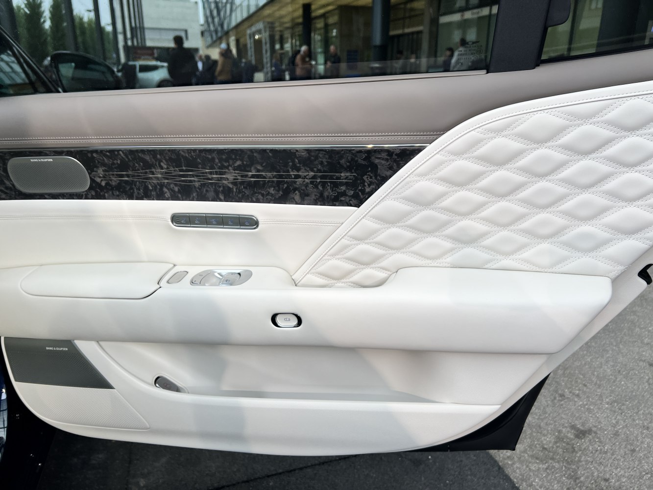 Diamond-quilted white leather door panel with integrated Bang & Olufsen speakers and control buttons