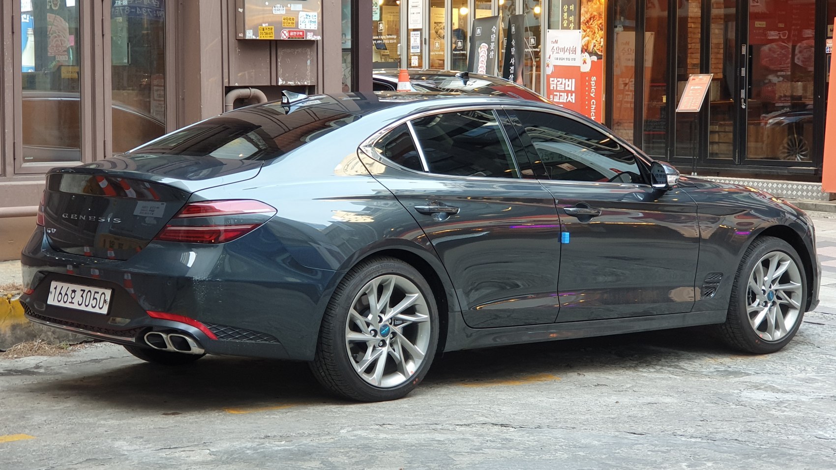 Rear and side profile of a luxury sedan with sporty exhaust and alloy wheels