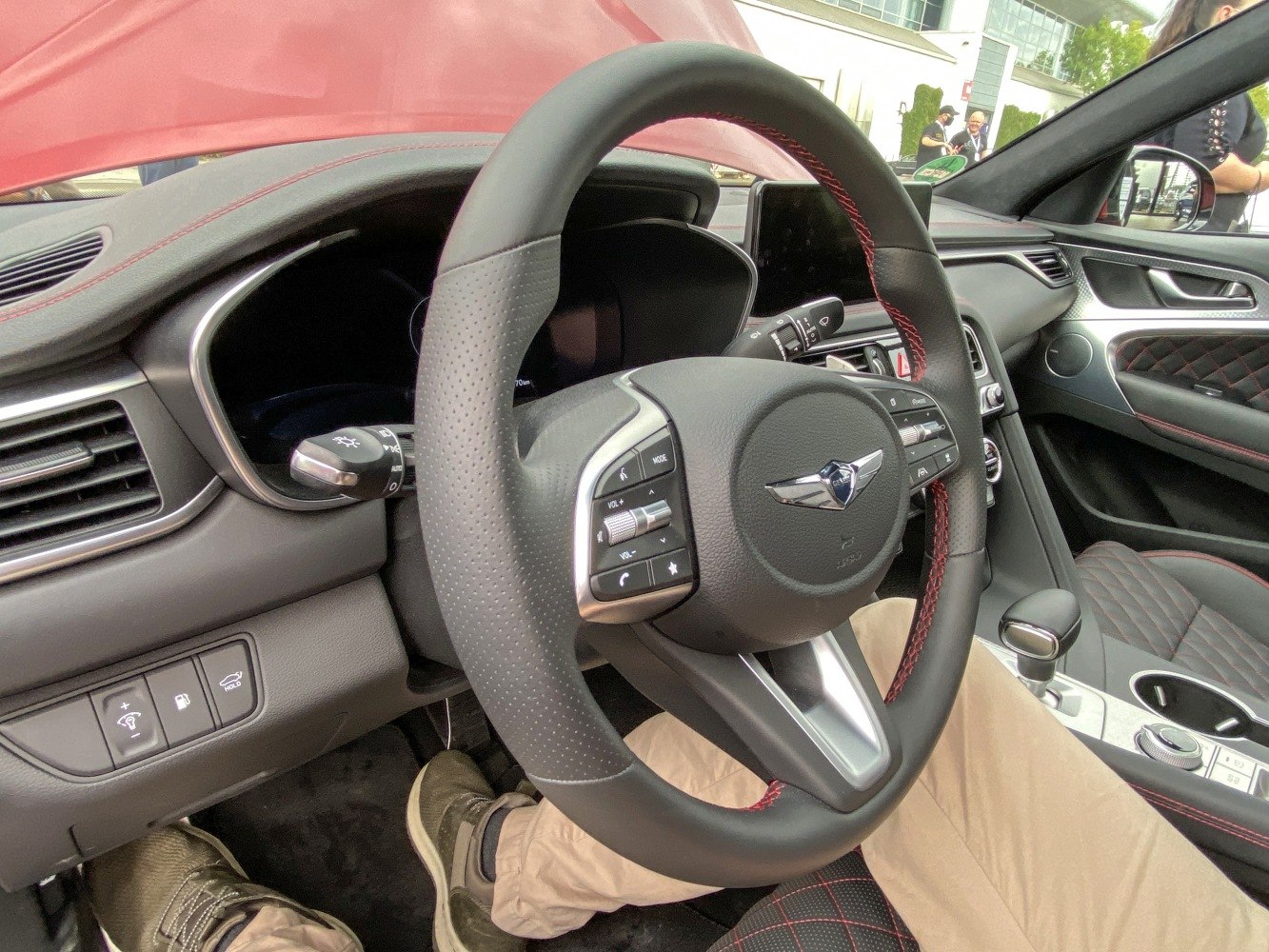 Leather steering wheel with red stitching and dashboard controls.