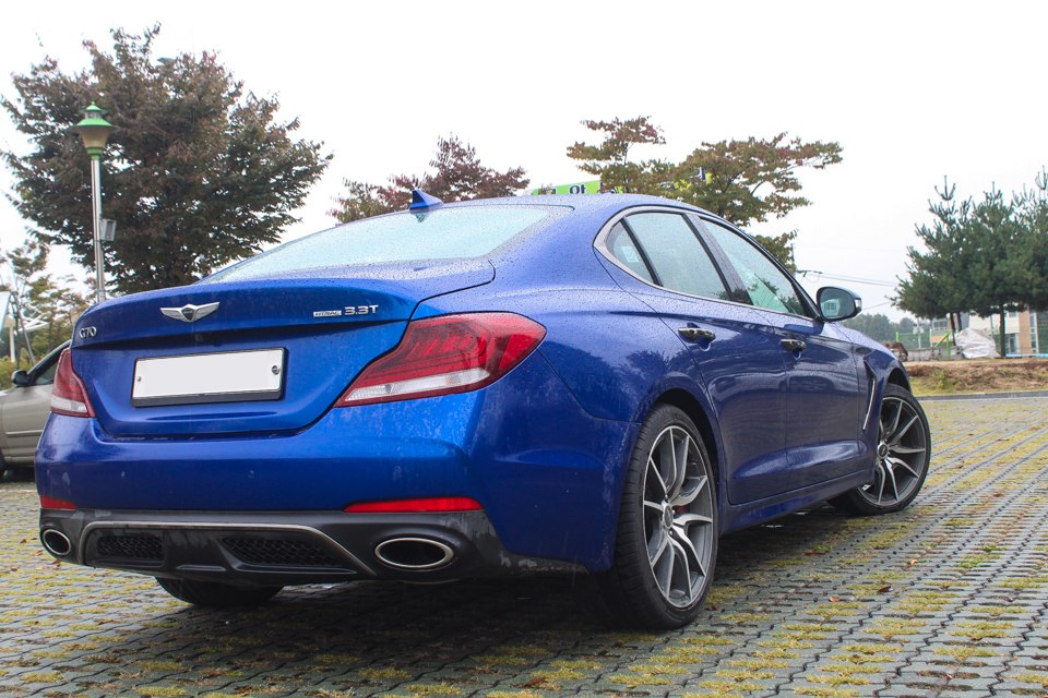 Blue sedan rear and side view with twin oval exhaust and sporty alloy wheels