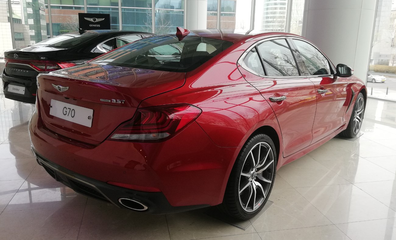 Rear and side view of red sedan with distinctive taillights and sporty alloy wheels