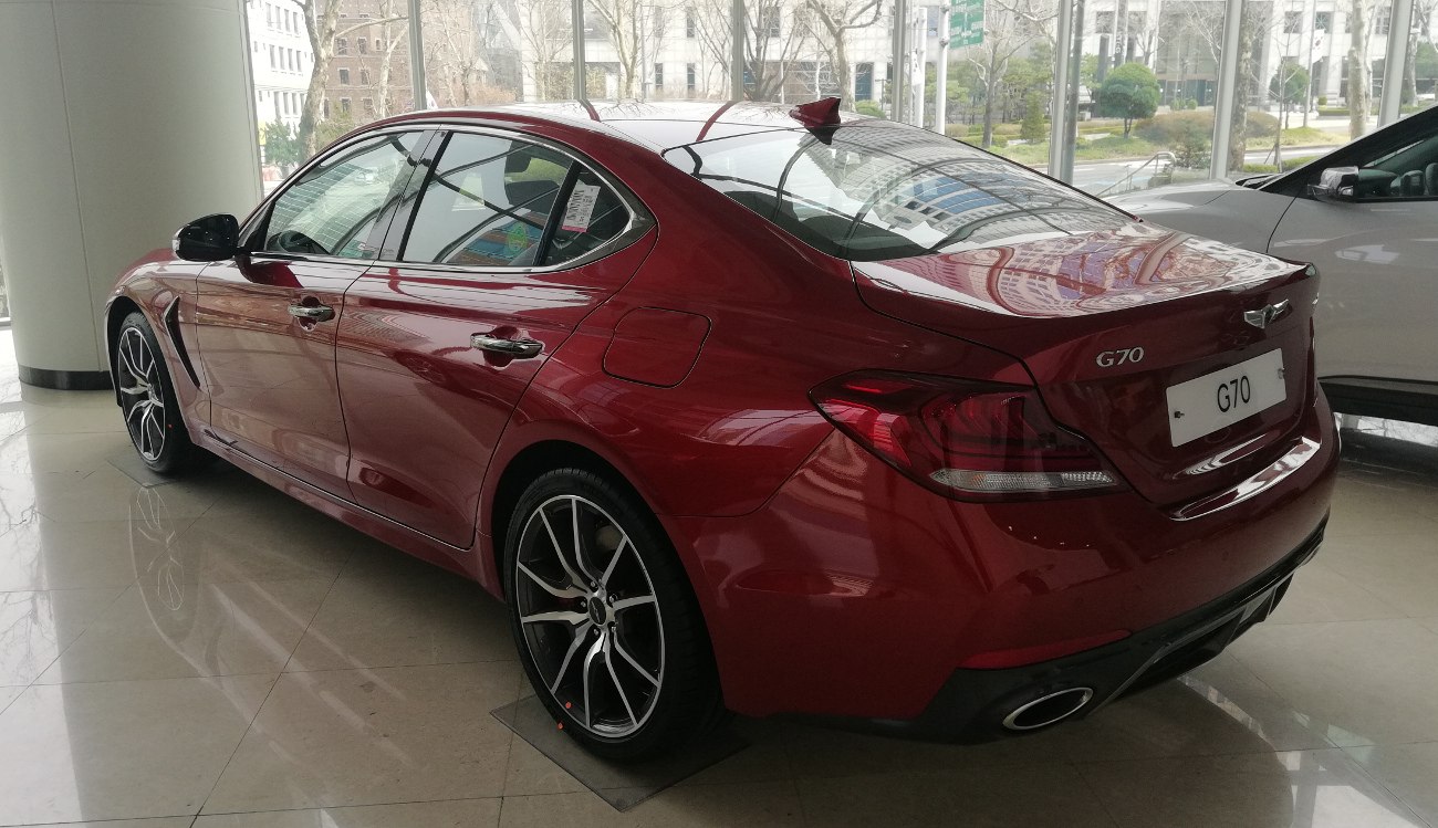 Rear-side view of a red luxury sedan with sporty wheels and dual exhaust