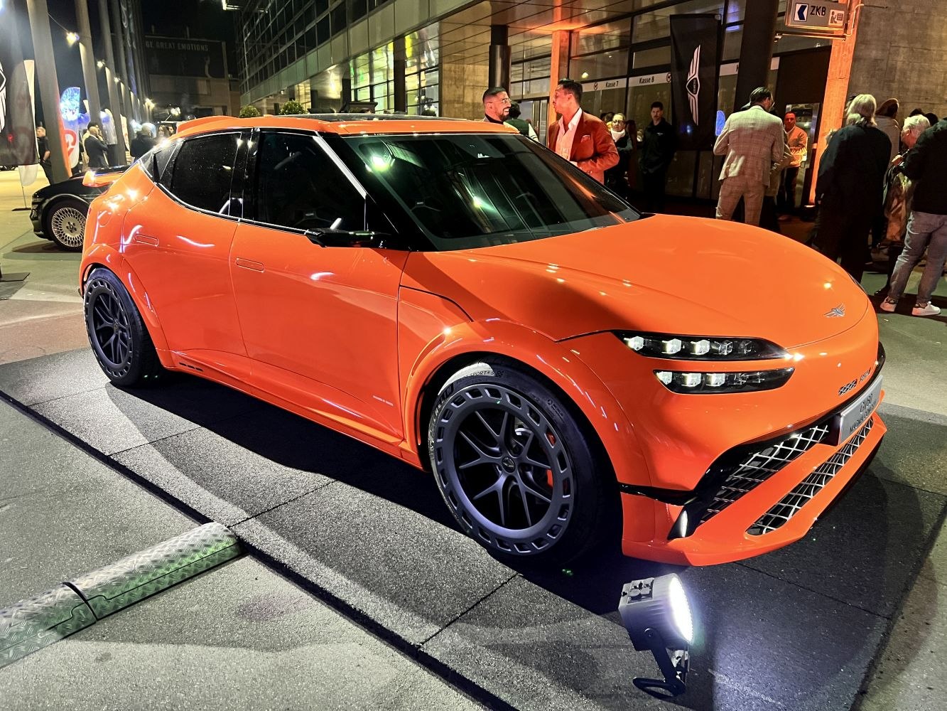 Orange electric SUV with futuristic headlights and wide sport wheels