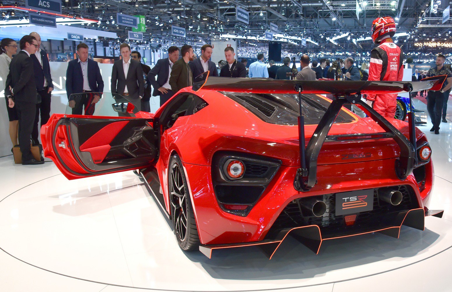 Rear view of a red high-performance sports car with open door and large rear carbon fiber spoiler