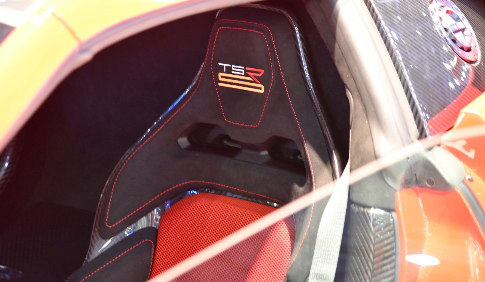 Racing seat with red stitching and carbon fiber panels