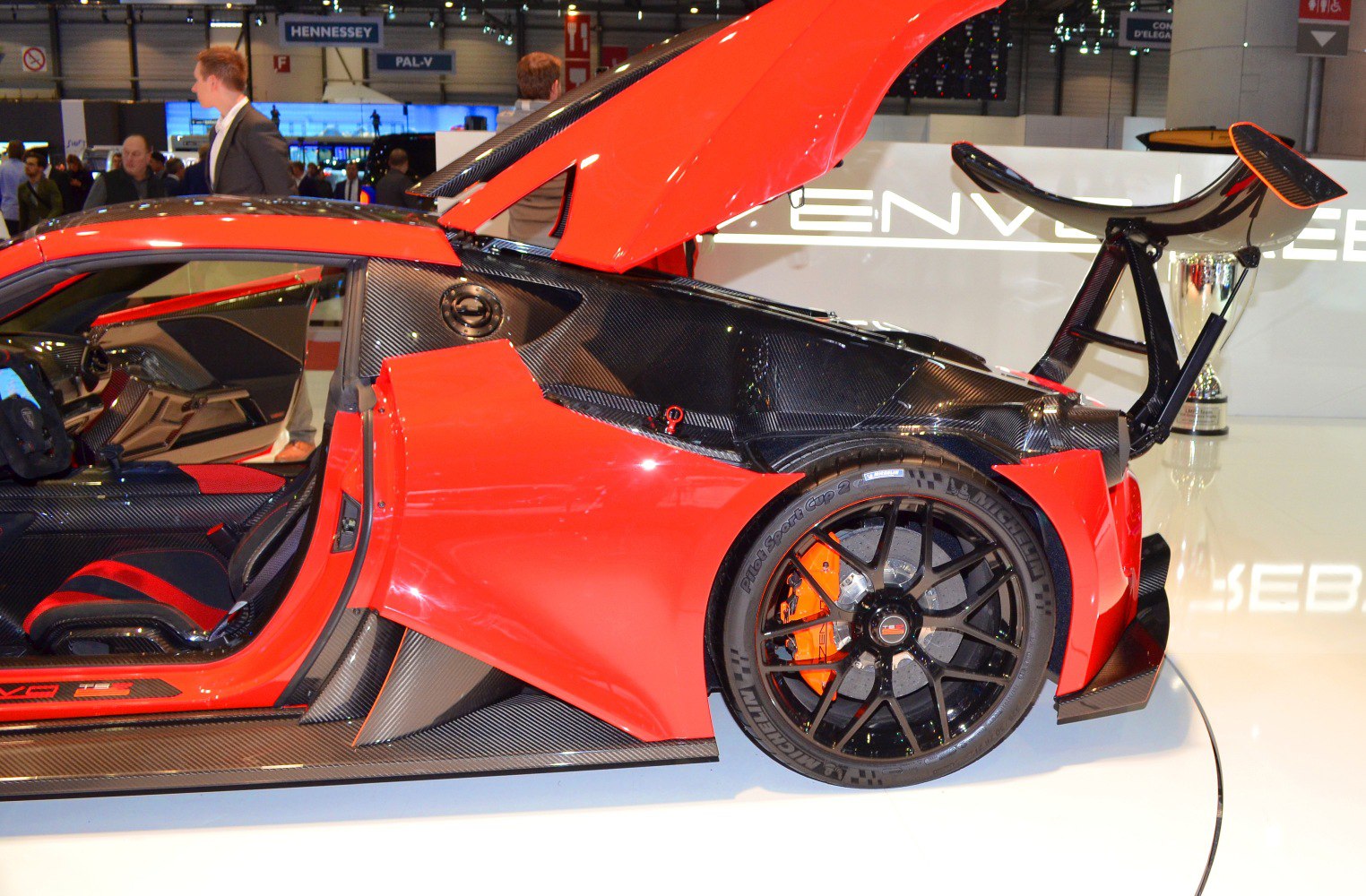 Rear side with open hatch, large rear wing, carbon fiber, and rear wheel with orange brake caliper