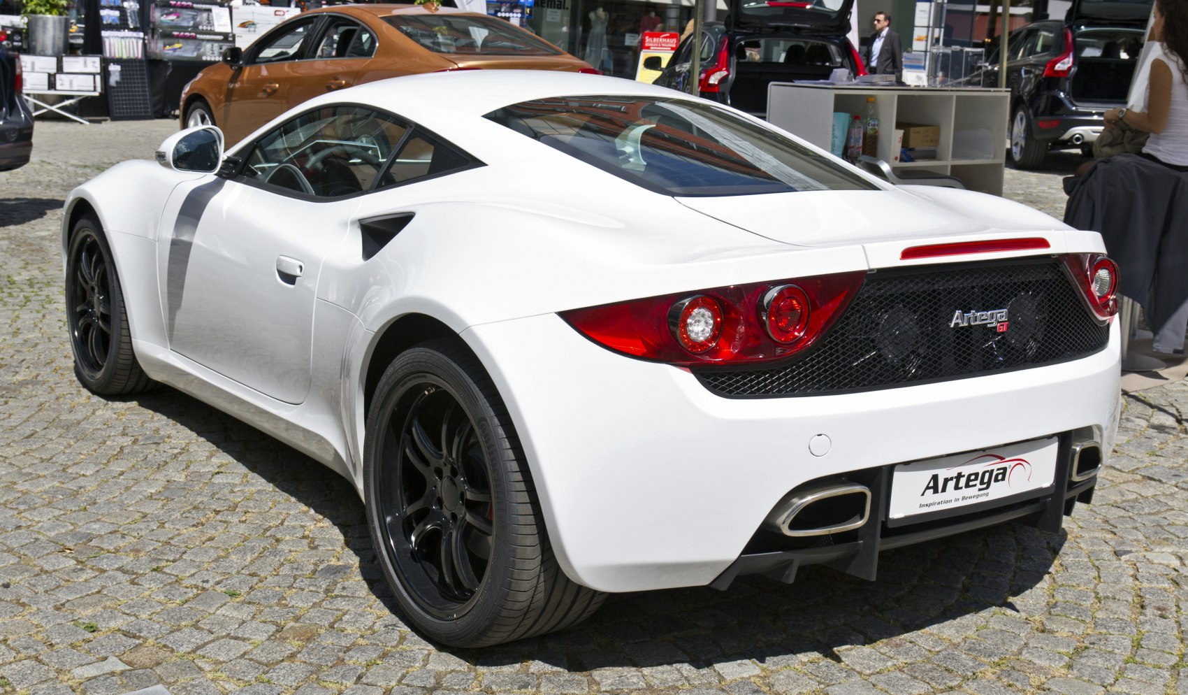 Rear view of a sleek white sporty coupe with black wheels and dual exhausts