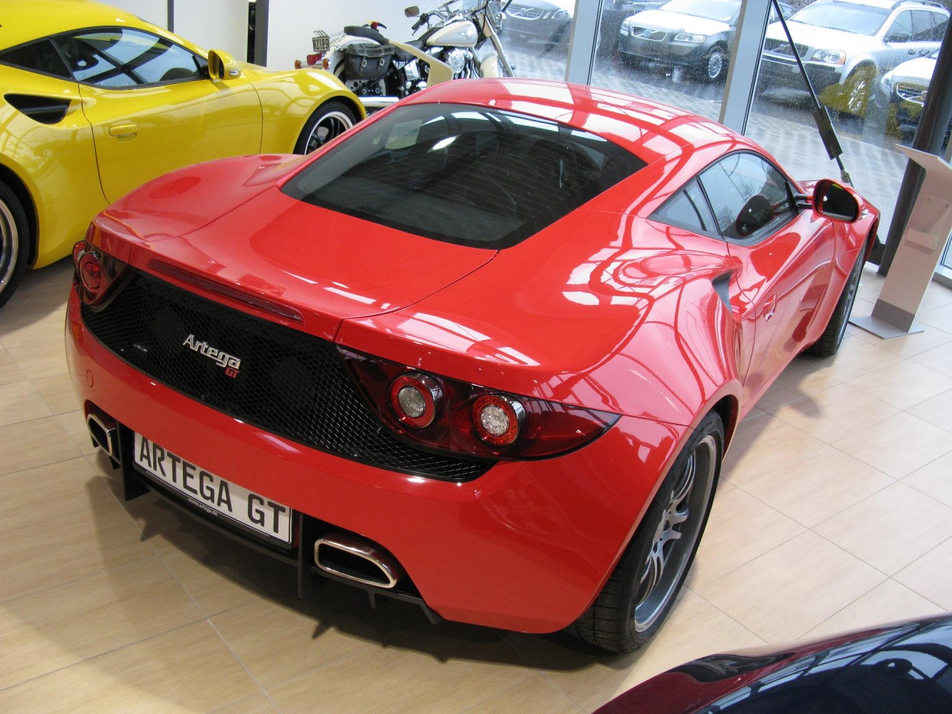 Rear and side view of red sports coupe with circular tail lights and dual exhaust