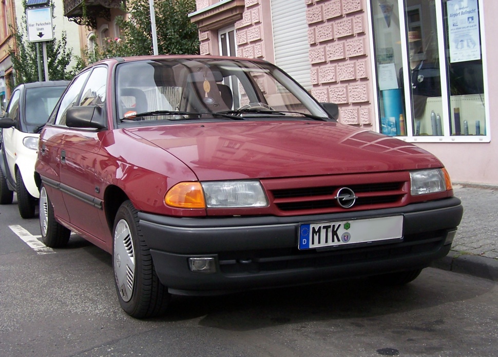 Front view of red hatchback with classic early 90s design and distinctive grille.