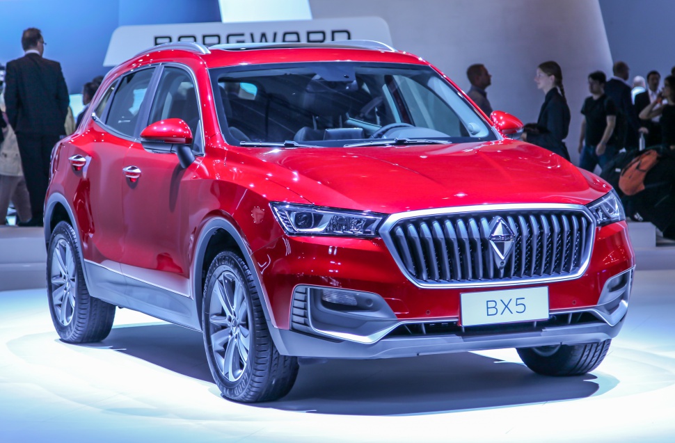 Red SUV with vertical grille and LED headlights under exhibition lighting